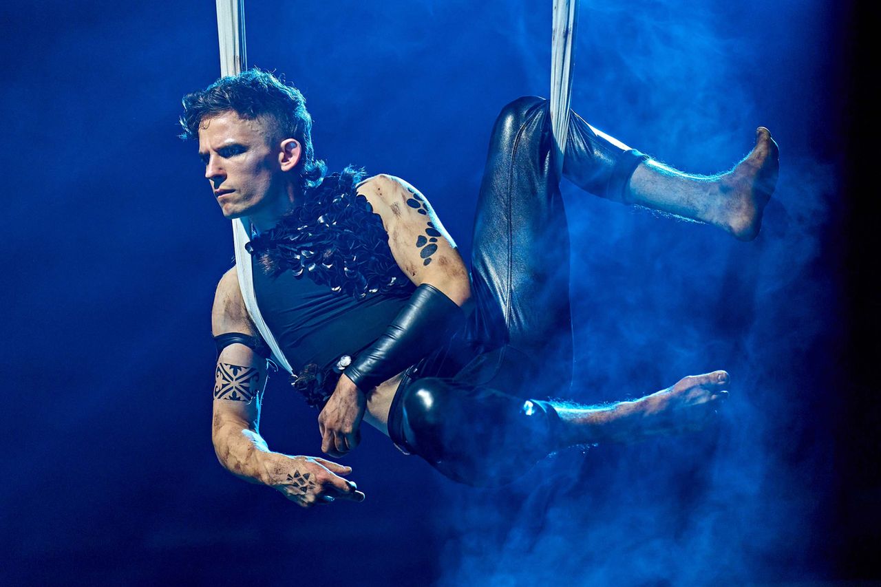 Puck, dressed in black, hanging from a hoist