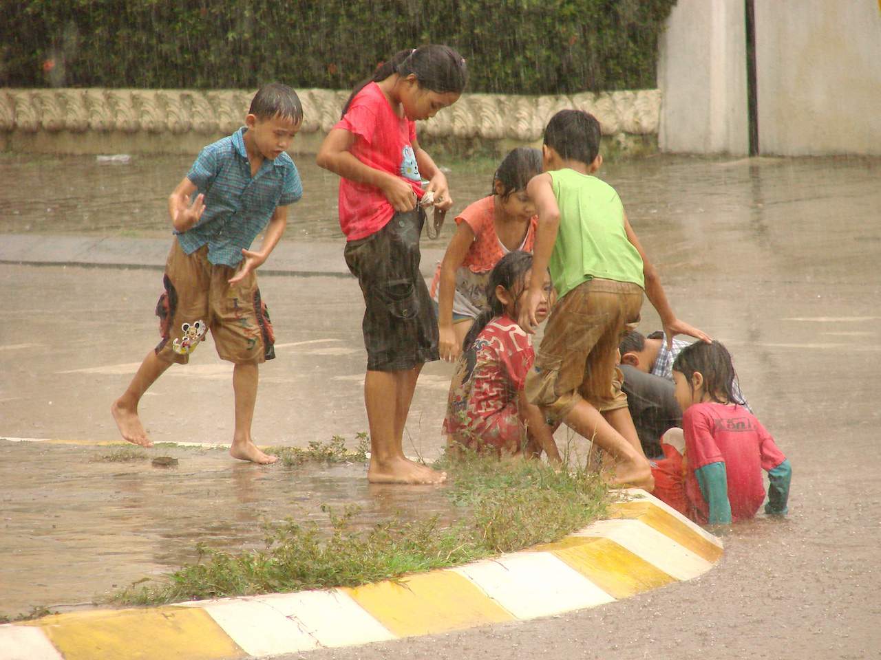 children play in monsoon downpour pakse laos