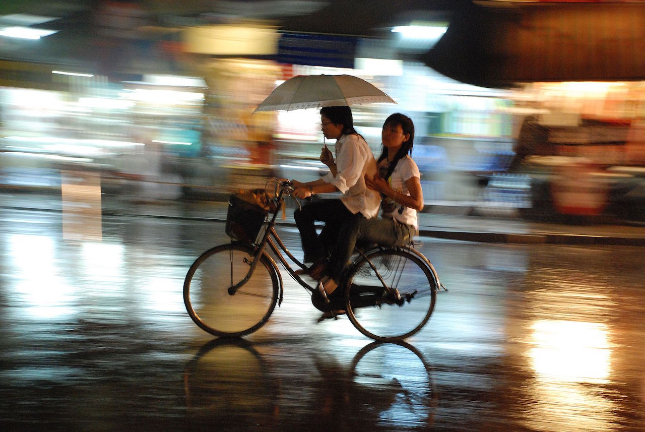 couple on the bycicle under the rain in hanoi vietnam